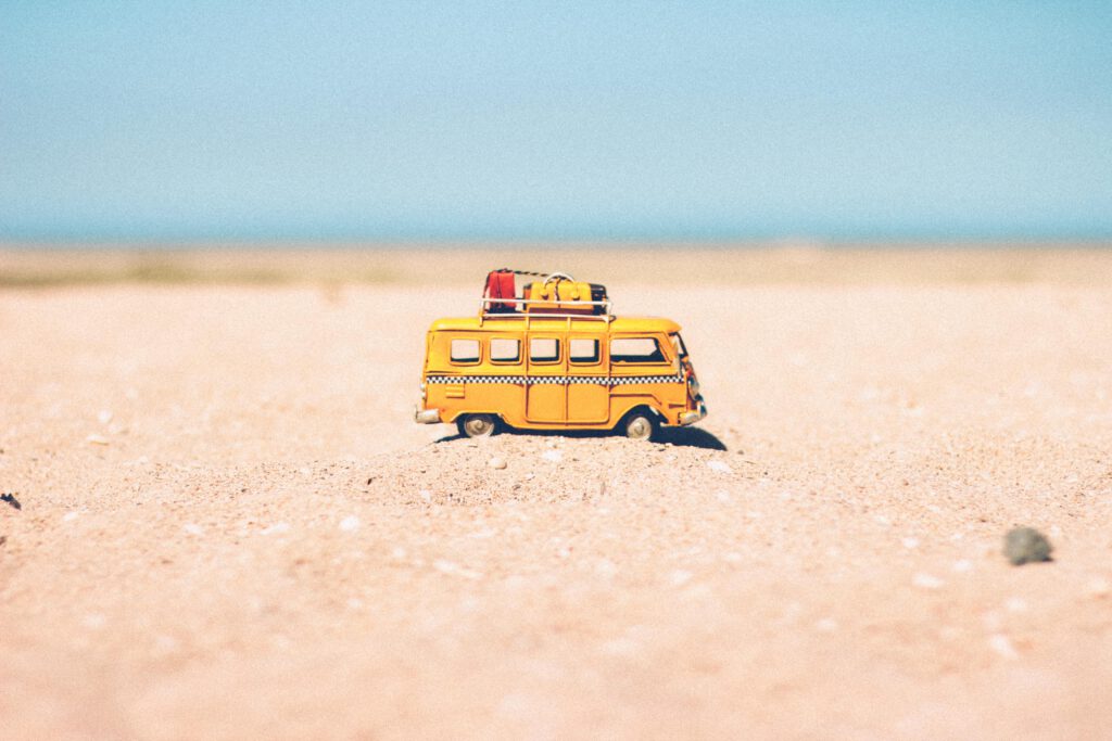 Ein gelber Autobus steht zentriert im Bild am Strand